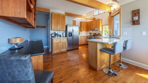 Een moderne keuken met houten kastjes, een centraal eiland met barkrukken en een inbouwoven.