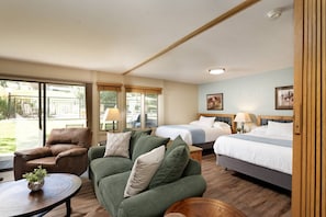Habitación de hotel con cama, dos sofás, una mesita de centro y vistas al exterior.