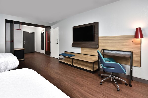 A hotel room with a bed, a desk with a chair, a TV mounted on the wall, and a red lamp. - Tru by Hilton Beckley (Beckley)