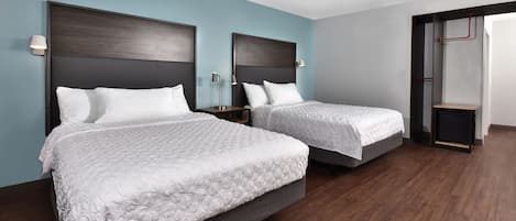 Una habitación de hotel con dos camas, piso de madera oscura y paredes azul claro.