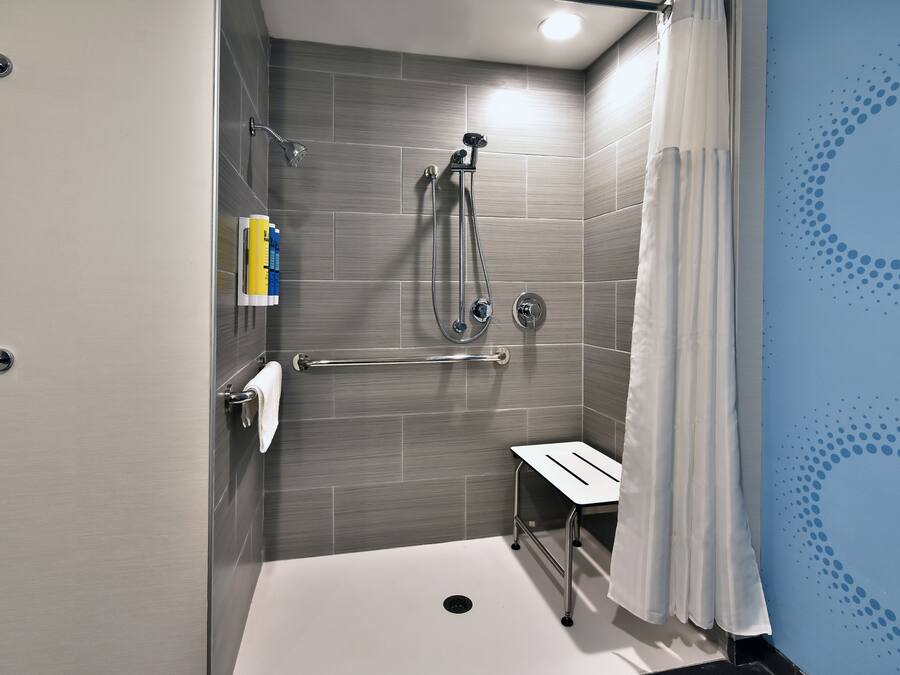 A modern shower area with a handheld showerhead, a handheld shower attachment, and a handheld shower nozzle.