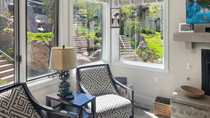 Una sala de estar con vistas a un jardín, una chimenea y un televisor sobre un mueble.