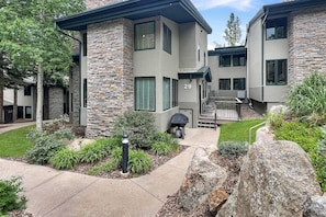 A modern two-story building with stone and concrete exterior, number 29, featuring a small deck and a covered outdoor seating area.