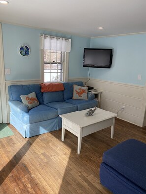 Cozy living space with a sofa, coffee table, and flat-screen TV.