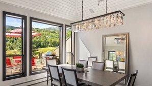En matplats med ett stort bord, stolar och utsikt över ett grönskande landskap genom stora fönster.