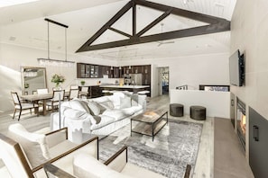 A spacious living area with a high ceiling, a dining table, and a sofa.