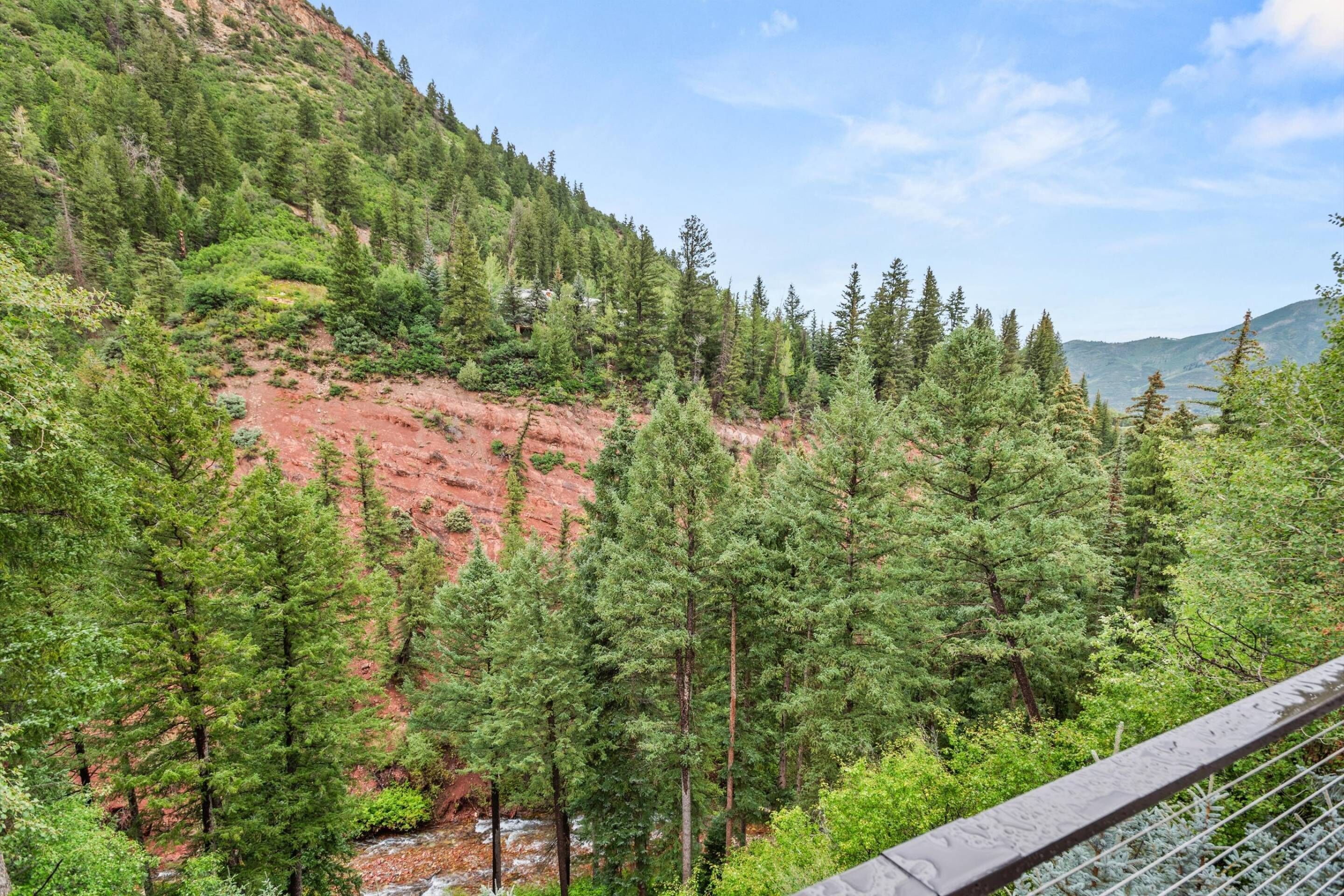 A forested mountain area with a bridge in the foreground.
