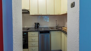 Una cocina compacta con lavavajillas, cafetera y pileta.