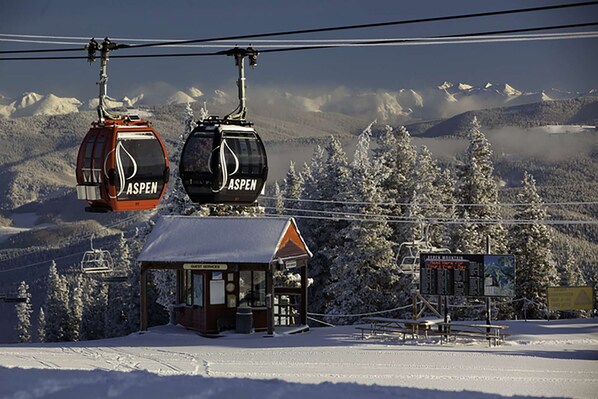 A ski lift with cabins labeled 'ASPEN' and a small building with a sign 'GOVERNMENT SERVICES'. - Lemond Place Home by iTrip Aspen Snowmass (Snowmass Village)