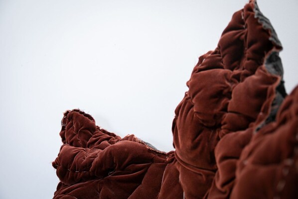 A close-up of a textured, brown fabric with a rugged, uneven surface.