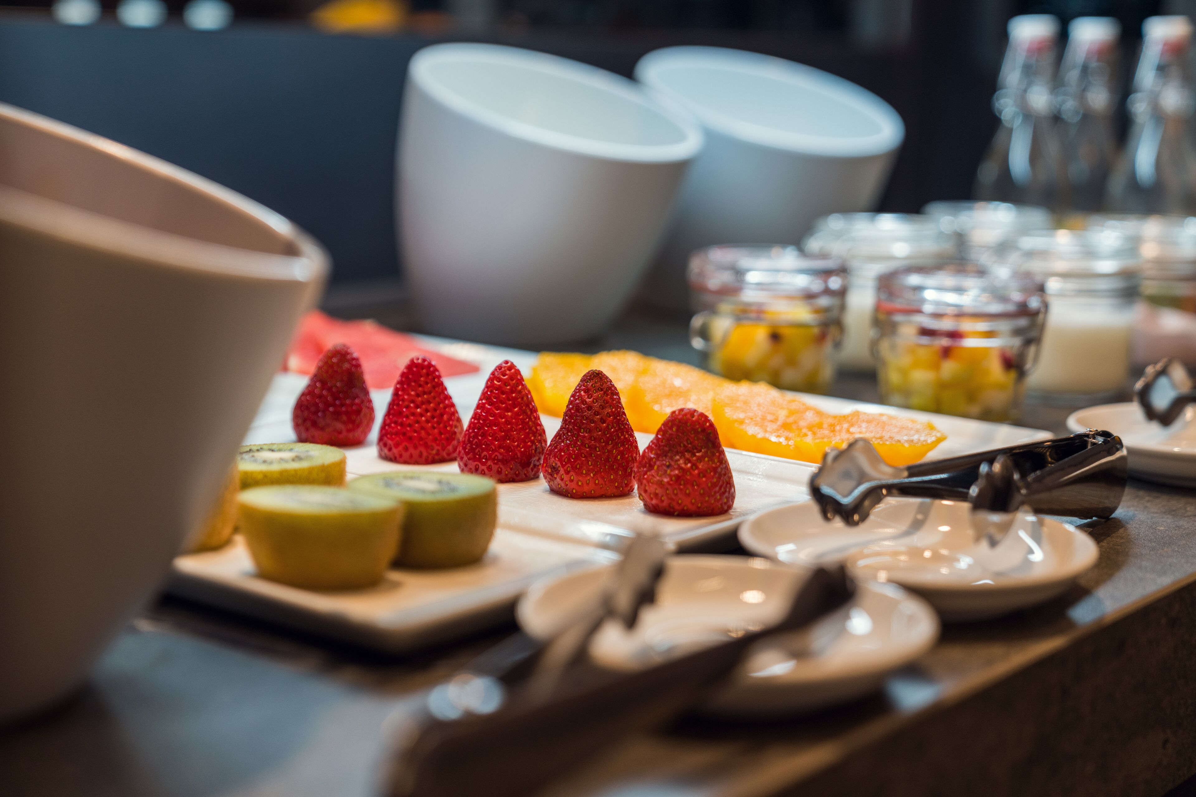 A breakfast buffet with various fruits and a coffee station.