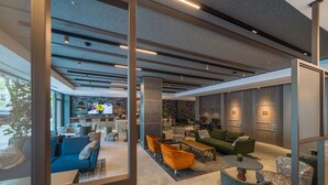 Un moderno vestíbulo de hotel con una zona de estar, un bar y una pantalla de televisión.