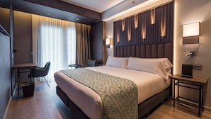 Una habitación de hotel moderna con una cama grande, un escritorio, una silla y una mesita.