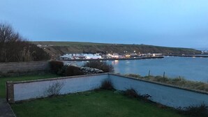 A waterfront property with a grassy area and a paved path leading to a dock. - Bungalow with sea-view, near small town of Thurso.  (Thurso)