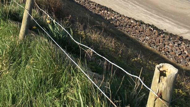 A coastal road with a beach, a rocky shoreline, and a distant town with buildings. - Bungalow with sea-view, near small town of Thurso.  (Thurso)