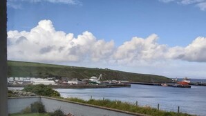 A coastal view with a grassy area, a paved path, and a body of water. - Bungalow with sea-view, near small town of Thurso.  (Thurso)