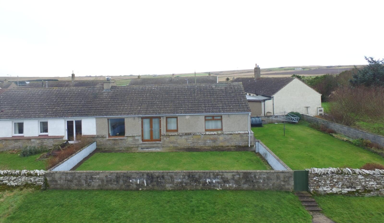A single-story house with a tiled roof, a front door, and a small front yard.