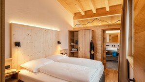A wooden bedroom with a bed, bedside tables, and a wardrobe. - Chalet houses (Oetz)