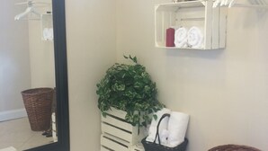 A bathroom with a large mirror, a potted plant, a white towel rack, and a wicker basket. - Chic and Comfortable Studio Free Street Parking (Miami)