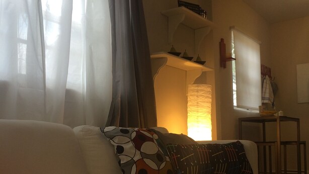 A living room with a white sofa, patterned cushions, a red throw blanket, and a black and white polka dot rug. - Chic and Comfortable Studio Free Street Parking (Miami)