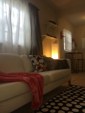A living room with a white sofa, patterned cushions, a red throw blanket, and a black and white polka dot rug. - Chic and Comfortable Studio Free Street Parking (Miami)