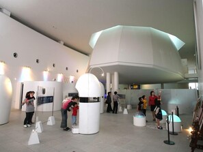 A modern interior with a large, white, dome-shaped structure, a few people interacting with exhibits, and a clean, minimalist design. - Hotel Tateyama (Tateyama)