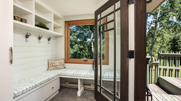 A cozy reading nook with a bench, shelves, and a window overlooking a garden. - Snowmass 2 Bedroom Private Outdoor Hot Tub by iTrip Aspen Snowmass (Snowmass Village)