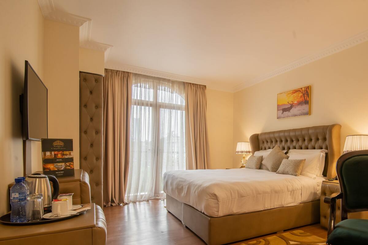 Une chambre d’hôtel avec un grand lit, une télévision, un bureau avec une lampe et une chaise.