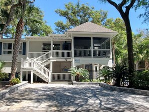 A two-story building with a balcony, a covered porch, and a stone pathway.