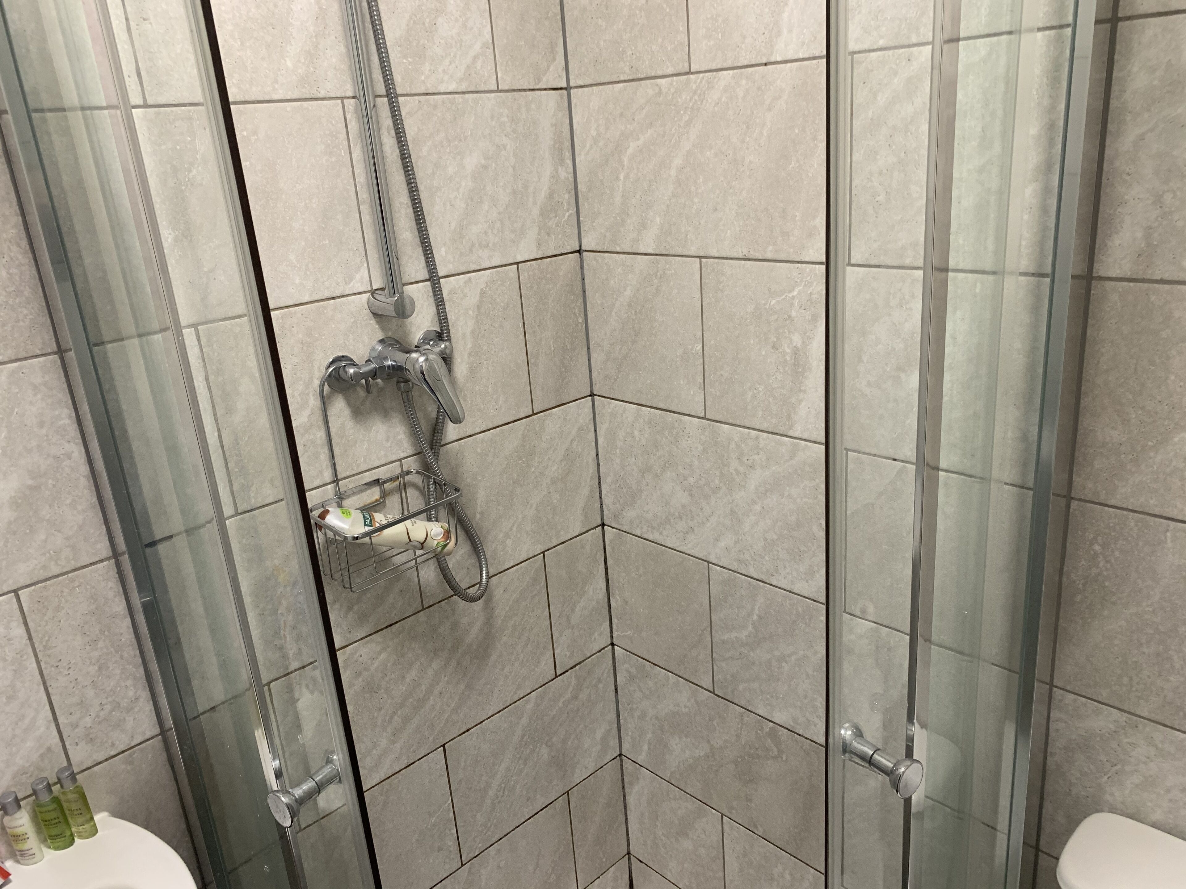 Une salle de bain avec une douche à parois de verre, une porte en verre et un sol carrelé.