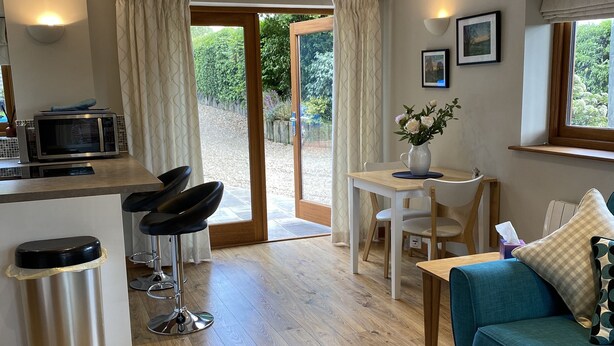 A compact living space with a kitchenette, a dining area, and a seating area with a sofa and chairs. - Rural Retreat in Warwickshire (Rowington)