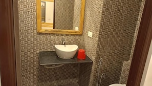 Un baño con paredes con diseño, un lavabo blanco y un espejo.