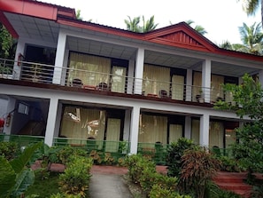 A two-story building with a red roof and white walls. It has multiple balconies with railings and potted plants. - Coconhuts Beach Resort-neil Island (Port Blair)