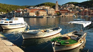 A harbor with boats docked, a prominent church tower, and a hillside town in the background.