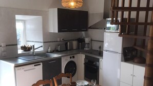 A modern kitchen with white cabinets, a built-in oven, a dishwasher, and a dining area with a table set for four.