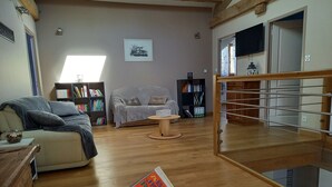 Un salon avec un canapé, une table basse, une bibliothèque et un plancher en bois.