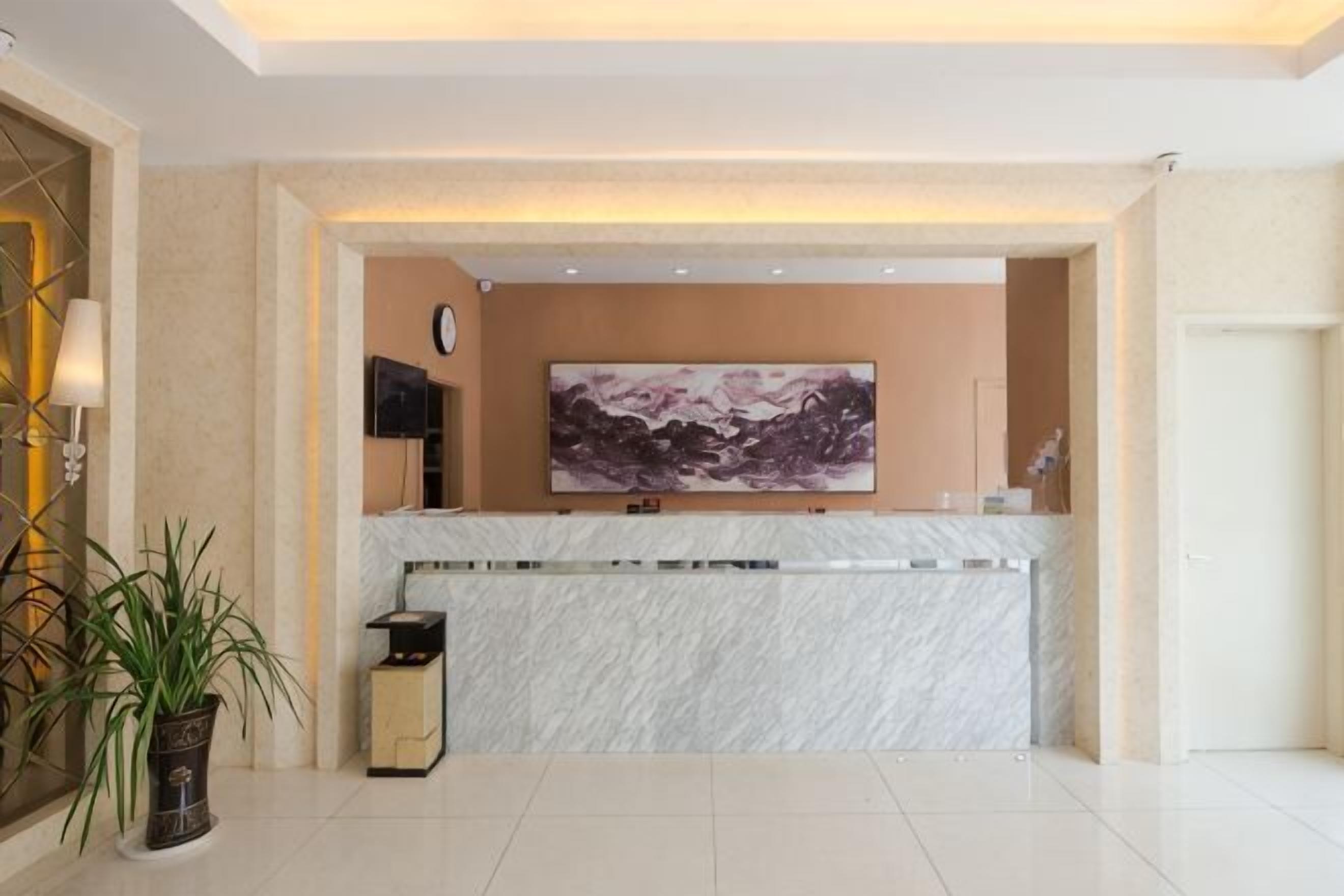 A reception area with a marble counter, a large framed artwork, a clock, and a potted plant.