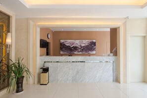 A reception area with a marble counter, a large framed artwork, a clock, and a potted plant. - Jinjiang Inn (Xianning Yinquan Avenue) (Xianning)