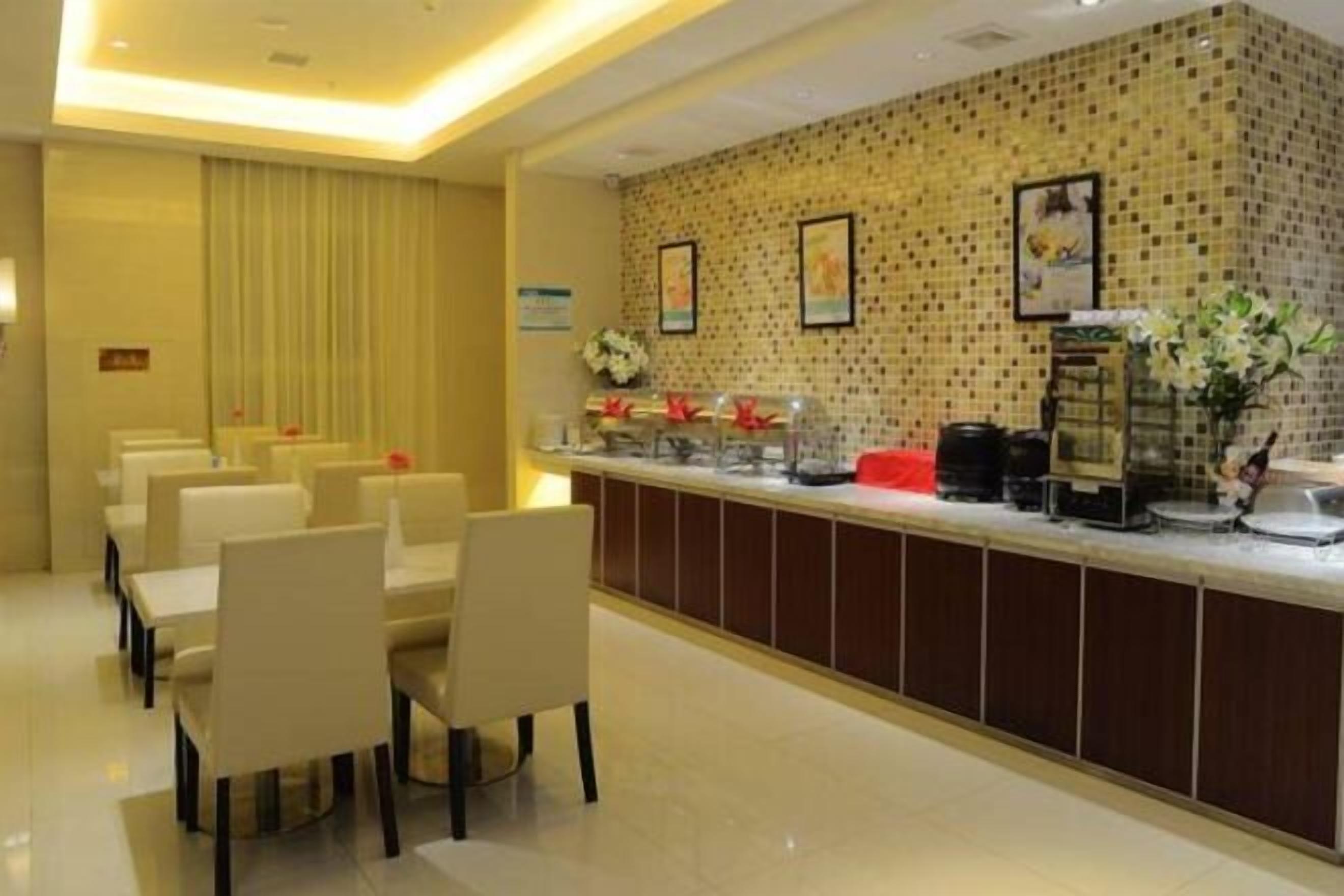 A hotel lobby with a reception desk, seating area, and a patterned wall.