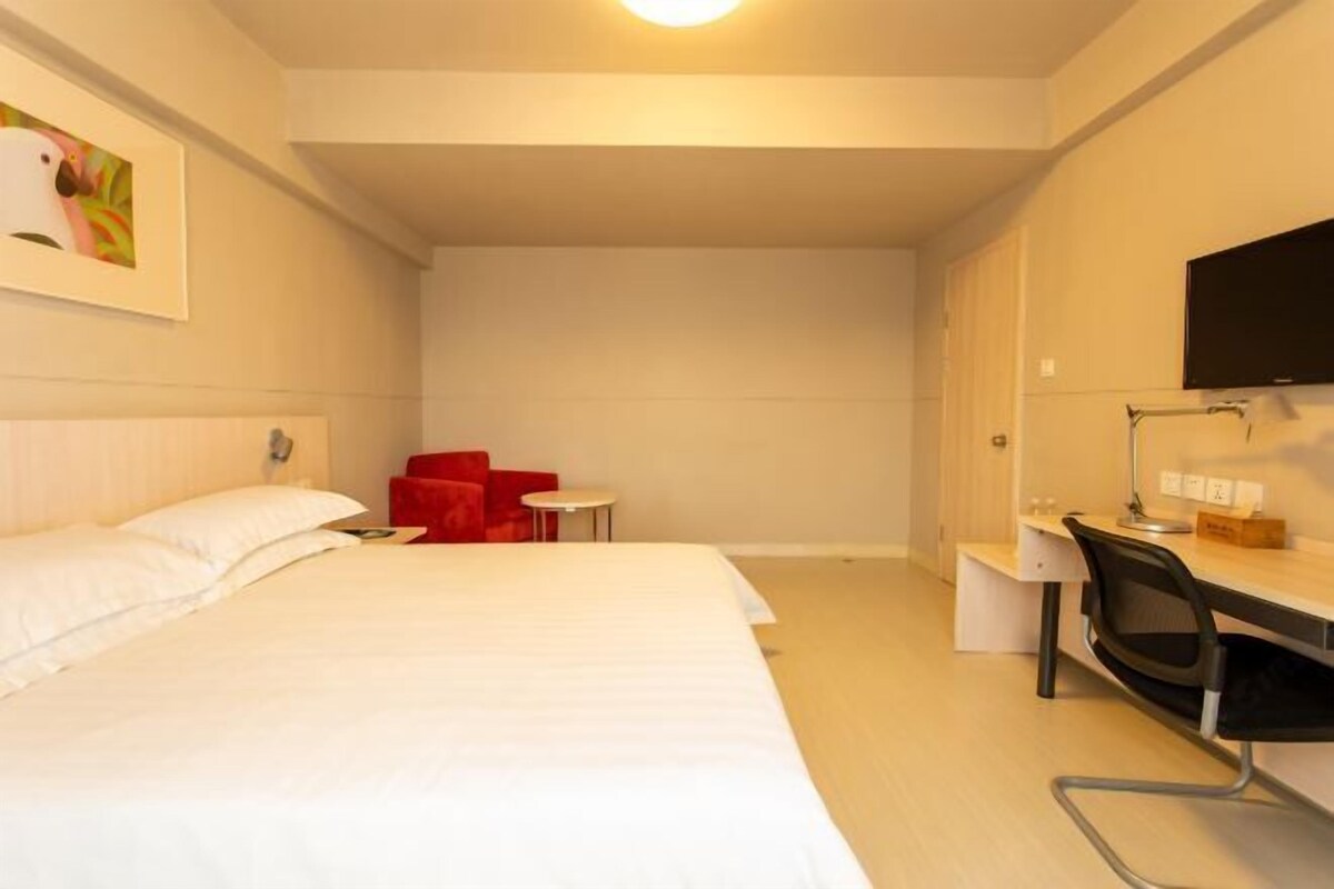 Une chambre d’hôtel avec un lit, un bureau, une chaise, une petite table et un téléviseur.