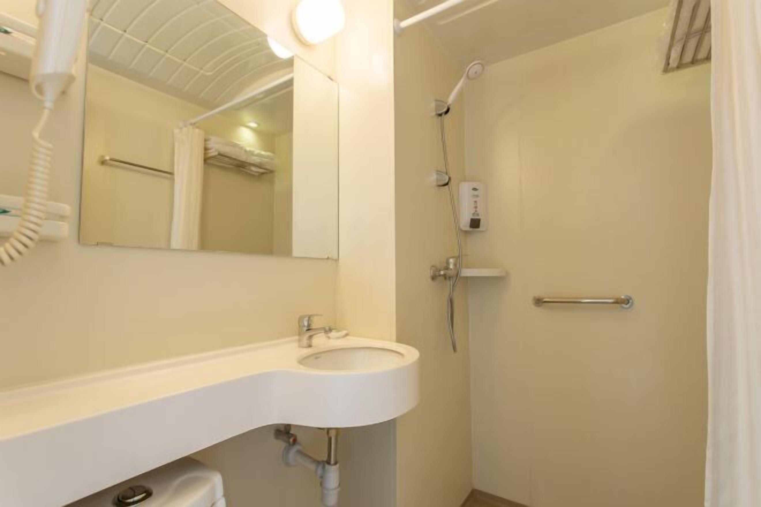 A bathroom with a sink, mirror, and shower.