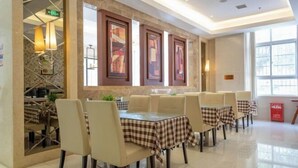 A dining area with tables and chairs, framed artwork on the wall, and a window providing natural light. - Jinjiang Inn (Xianning Yinquan Avenue) (Xianning)