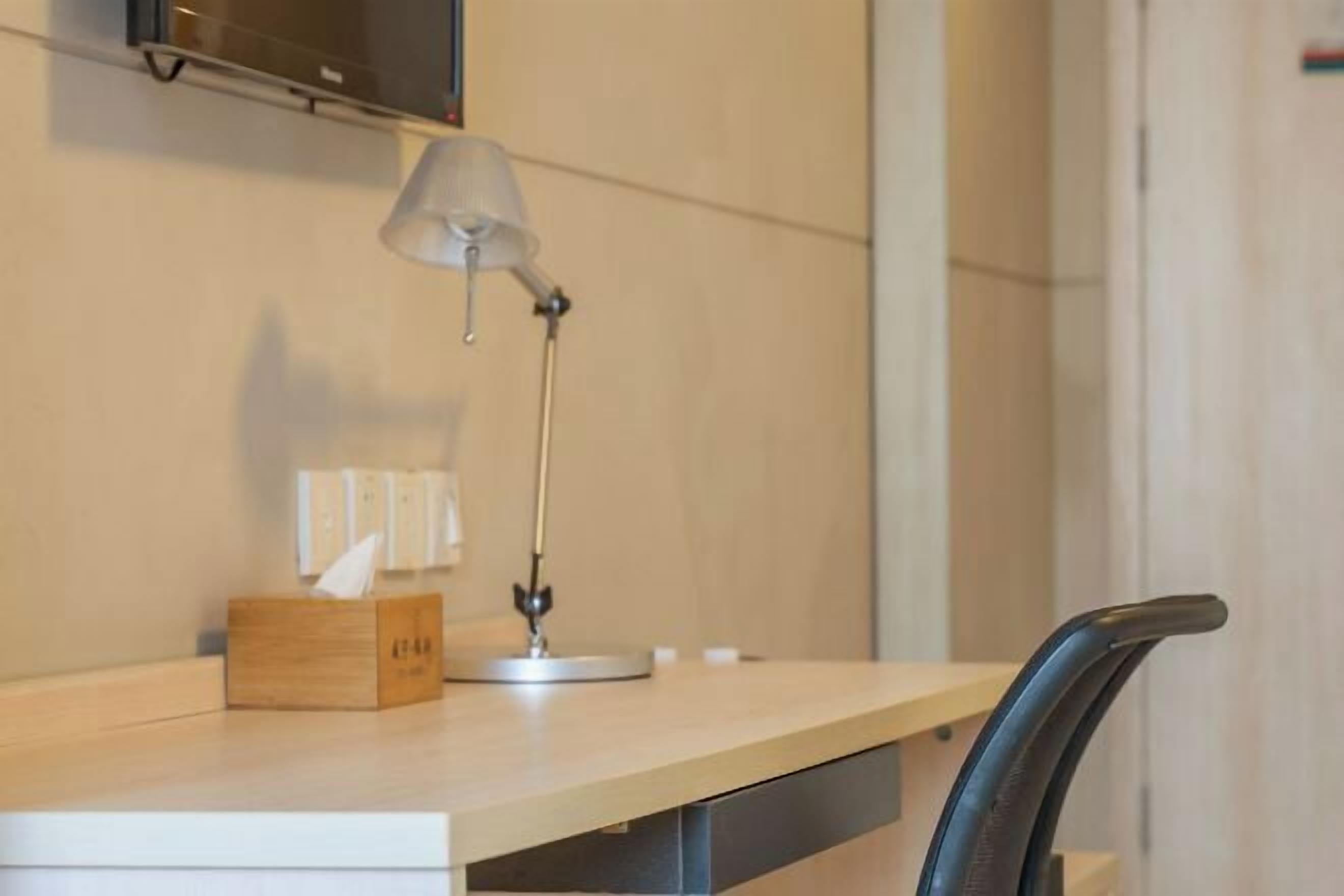 A desk with a lamp, a tissue box, and a chair.