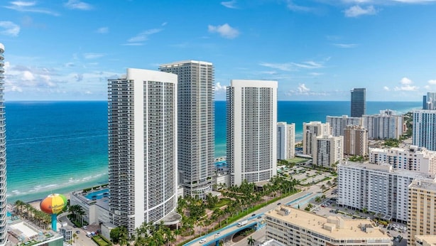 Un grand hôtel à plusieurs étages, doté d’une piscine et offrant une vue sur l’océan.