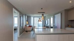 Une cuisine moderne dotée d’un îlot central, de luminaires suspendus et donnant sur l’espace repas.