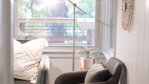 Una habitación acogedora con ventana, una silla, una cama y una lámpara.