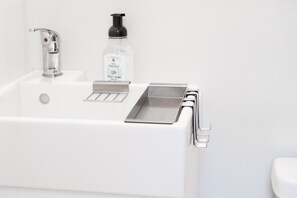 A modern bathroom with a white sink, a faucet, a soap dispenser, and a metal soap dish. - Minimalist-Style Apartment within walking distance of Downtown Johnson City (Johnson City)