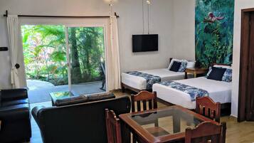 A hotel room with a ceiling fan, a TV, a mural, a sofa, a bed, and a dining table.
