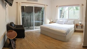 Un dormitorio con una cama grande, un ventanal corredero, un televisor de pantalla plana en la pared y una mesita de noche con lámpara.