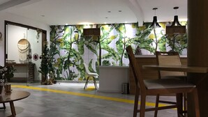 A modern interior with a tropical-themed wall, a reception desk, and seating areas. - Pipa Ubaia Residence Apartments (Tibau do Sul)